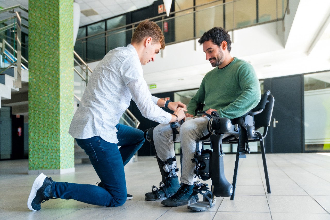 Mechanical exoskeleton, Physiotherapist placing the tapes on the knees of the disabled person to place his robotic skeleton, physiotherapy in a modern hospital: