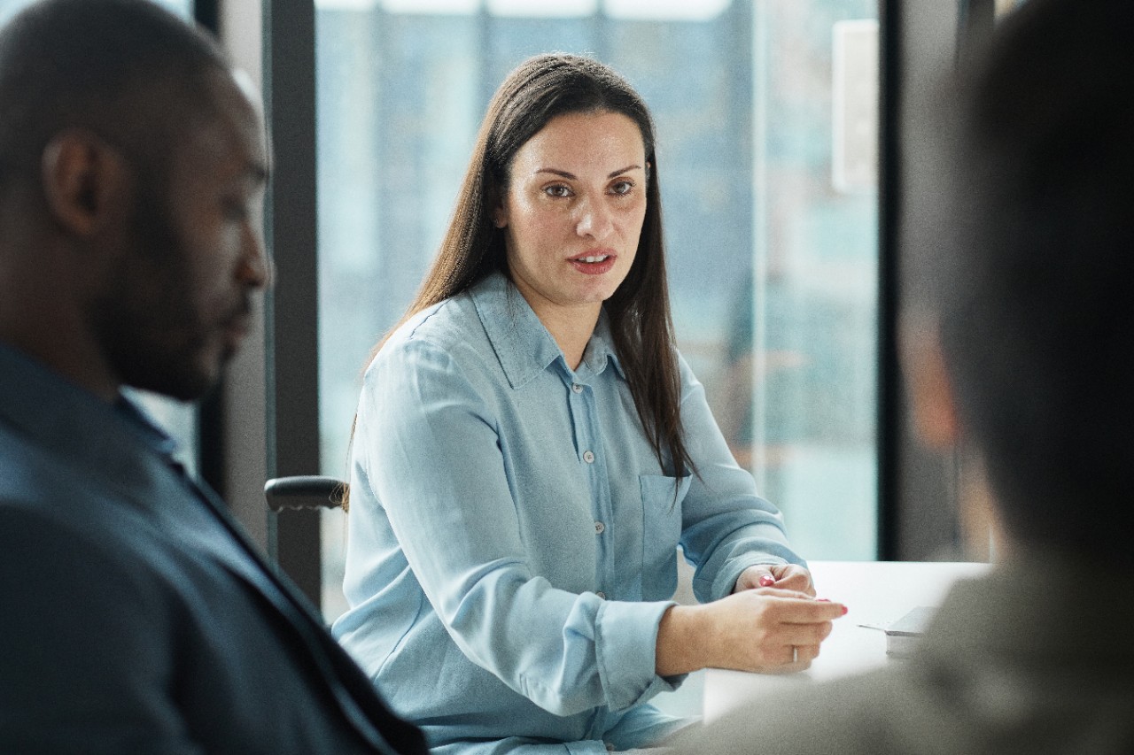 Portrait of modern disabled businesswoman leading meeting with business team in office, copy space
